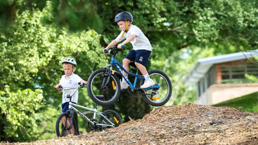 Tudor House student riding bike and going over a small jump