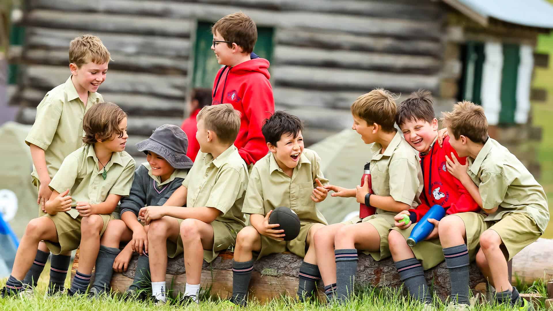 Tudor House students sitting on a log, laughing and interacting