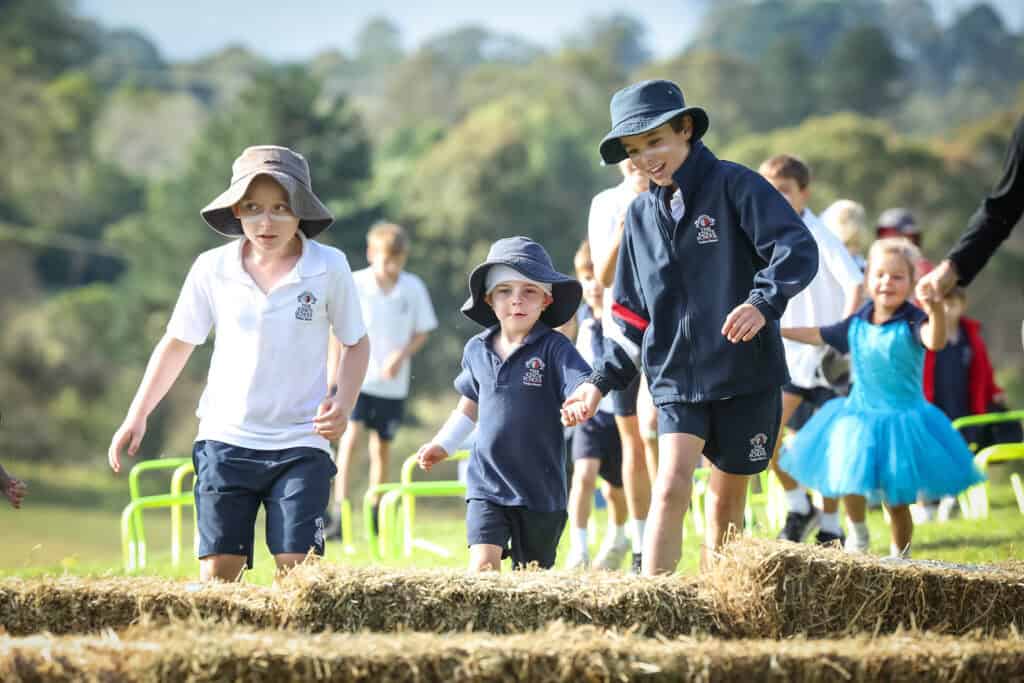 Older Tudor House student helping younger students complete a run competition for cross country