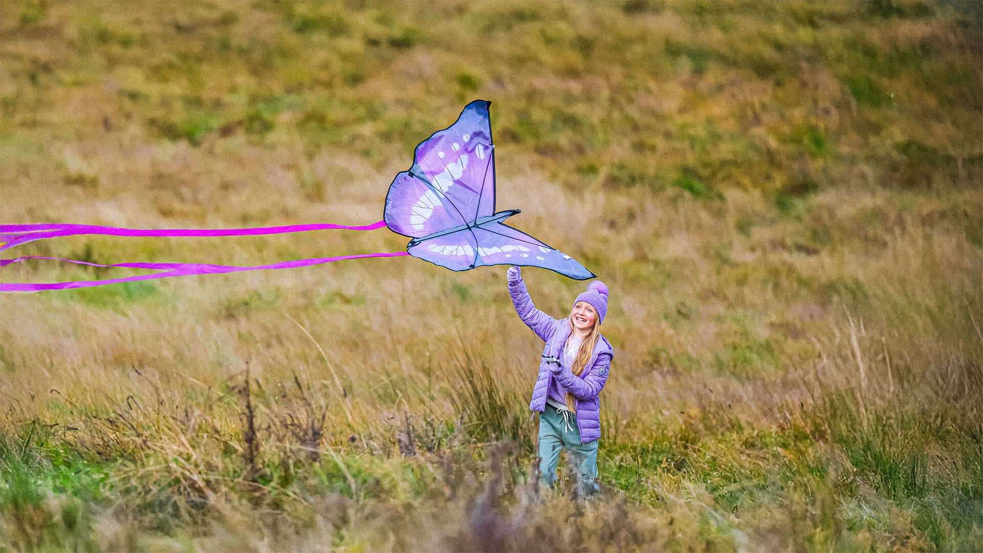 Tudor House student holding a purple butterfly kite in a grassy field