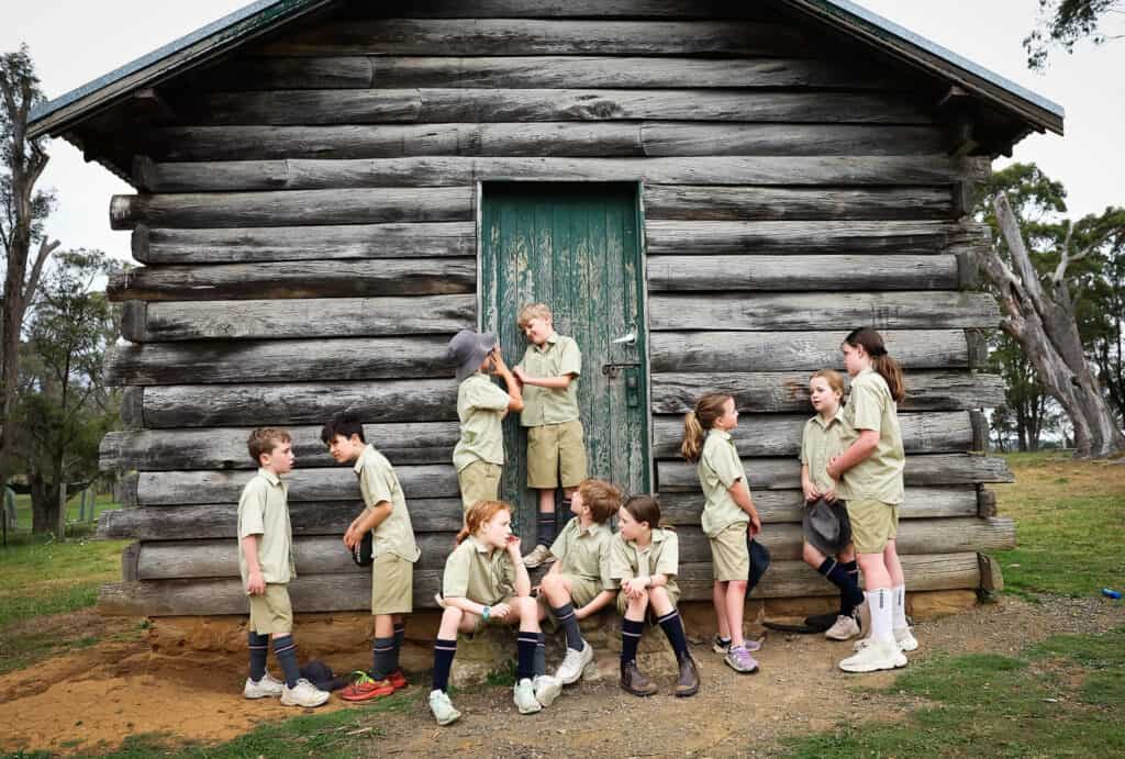 Tudor House students standing against an old historic building on campus and talking to each other