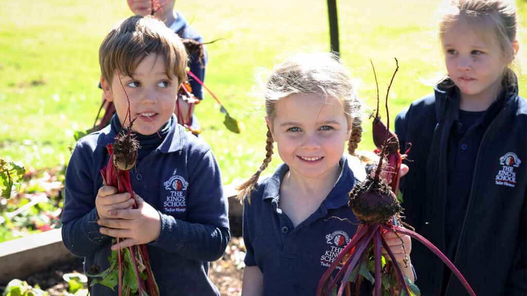 Tudor House pre-kindergarten students picking vegetables from the dirt and showing them