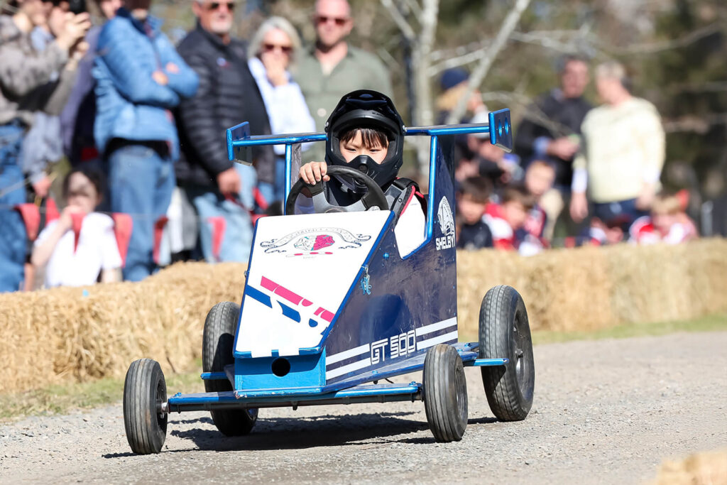 Tudor House student driving a billy cart at Billy Cart Derby Day