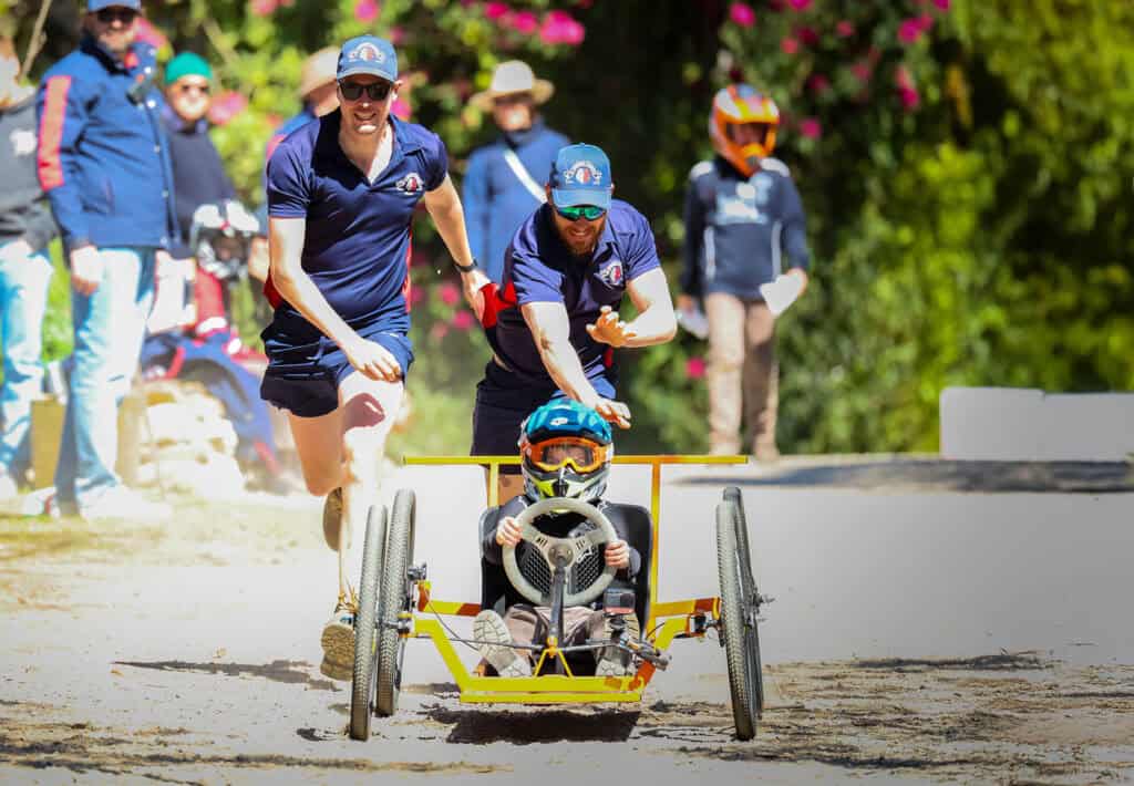 Tudor House Staff pushing a Billy Cart with a student with it