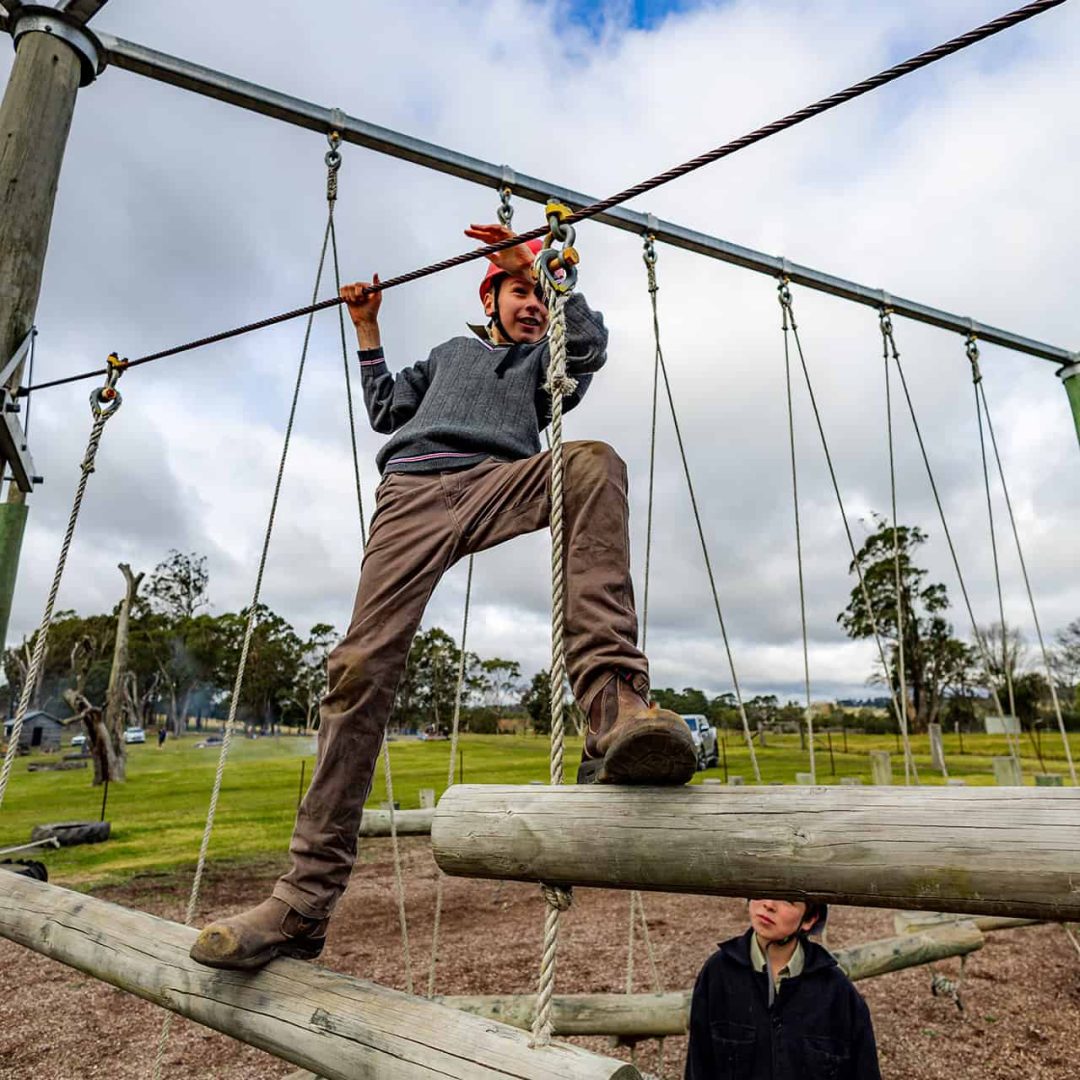 Tudor House student walking across logs in the high ropes course