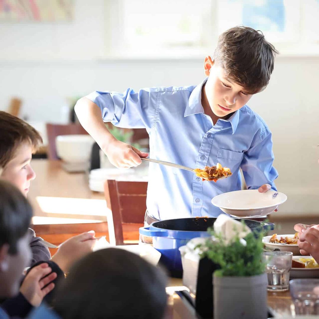 Tudor House boarding student serving food n the dining hall