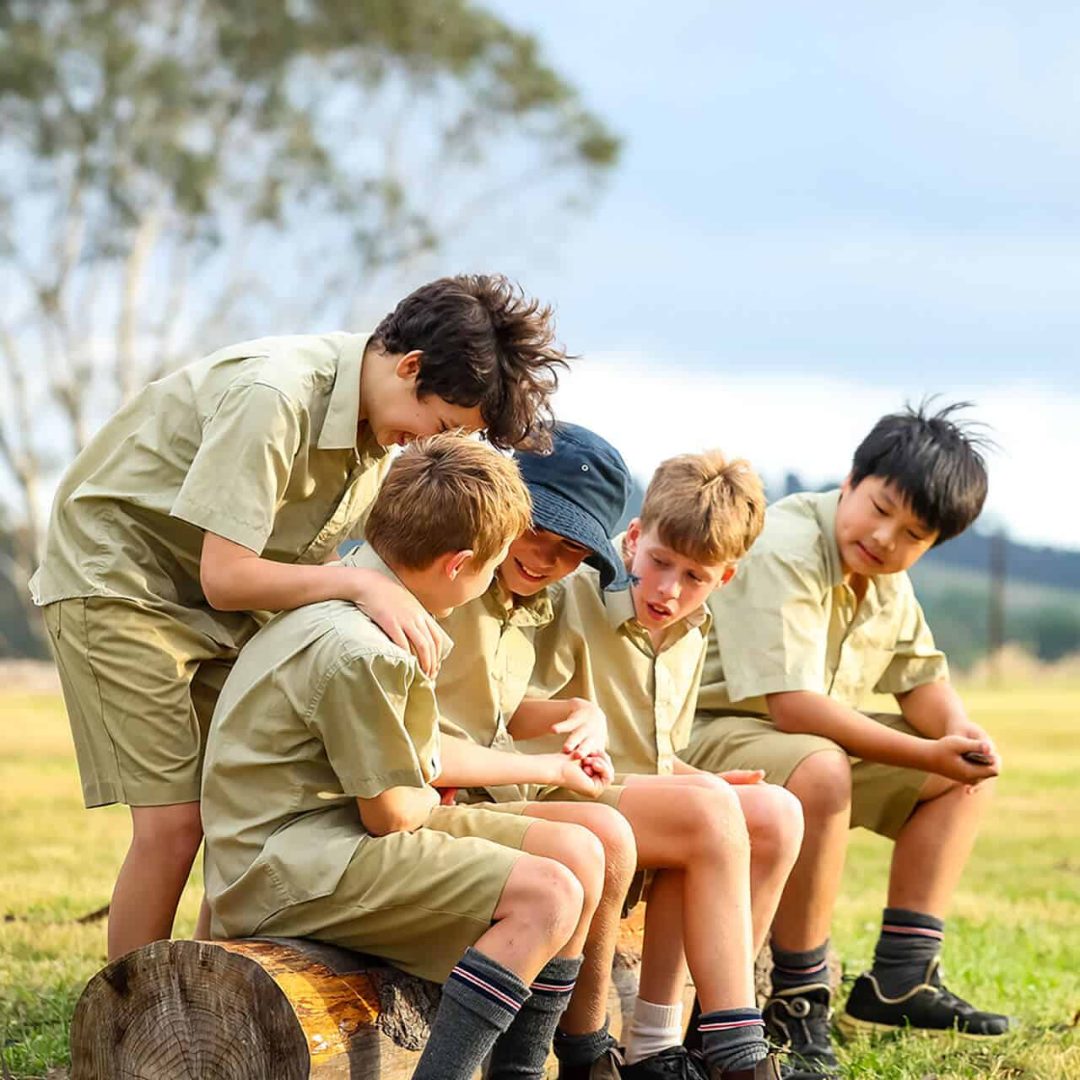 Tudor House students sitting on a log outdoors at Kahiba