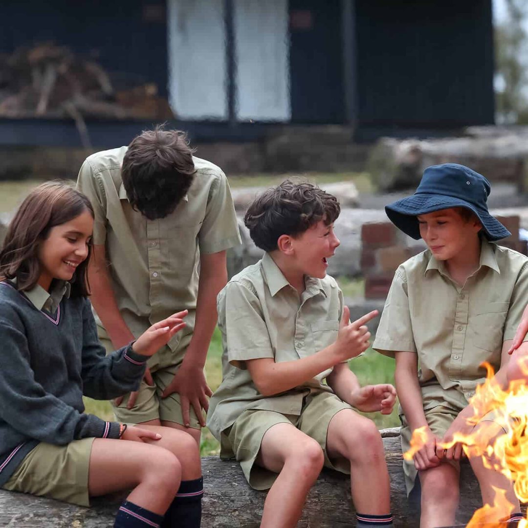Tudor House students sitting by a campfire and laughing